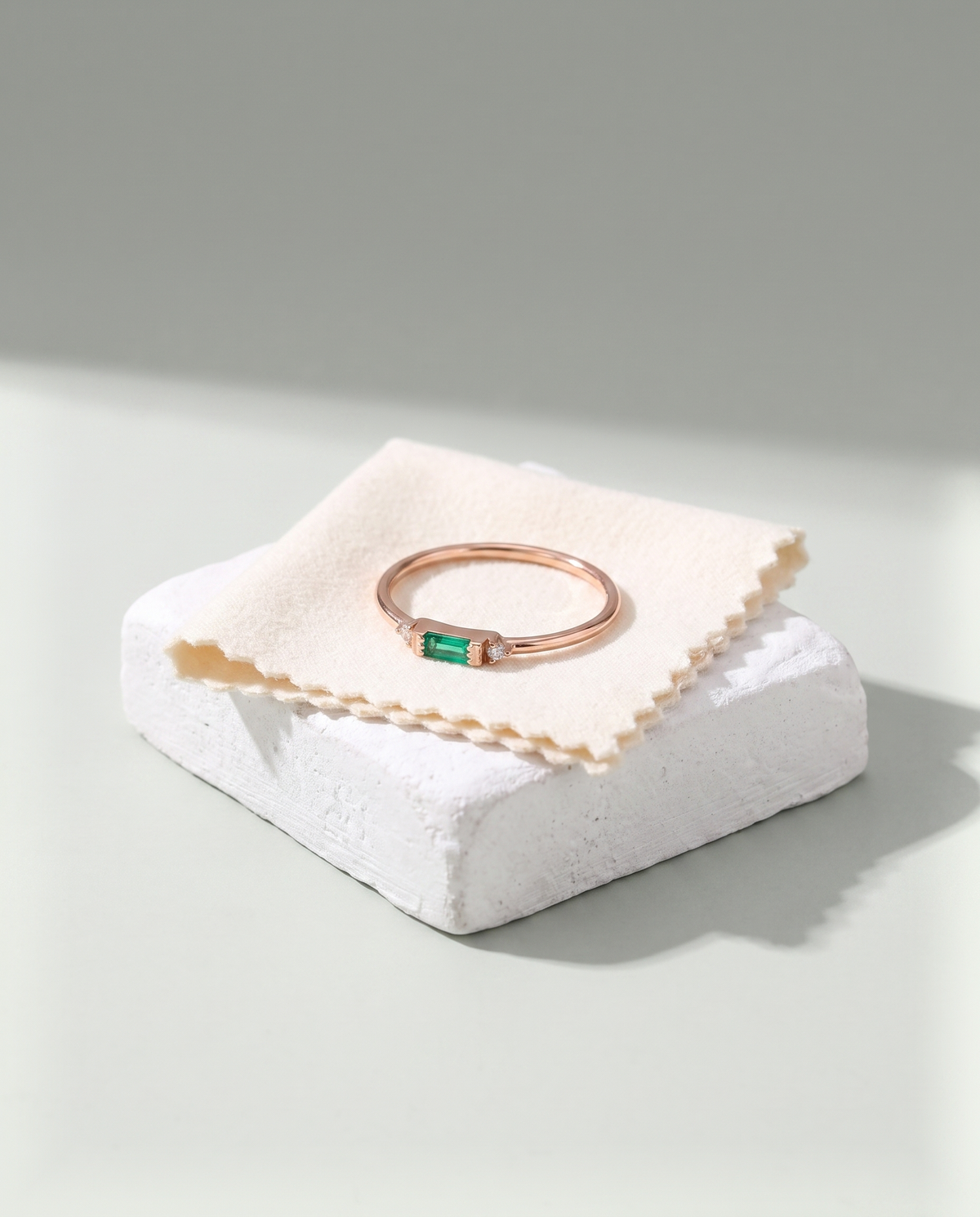 A finished rose gold ring resting on a folded cotton polishing cloth over a plaster block