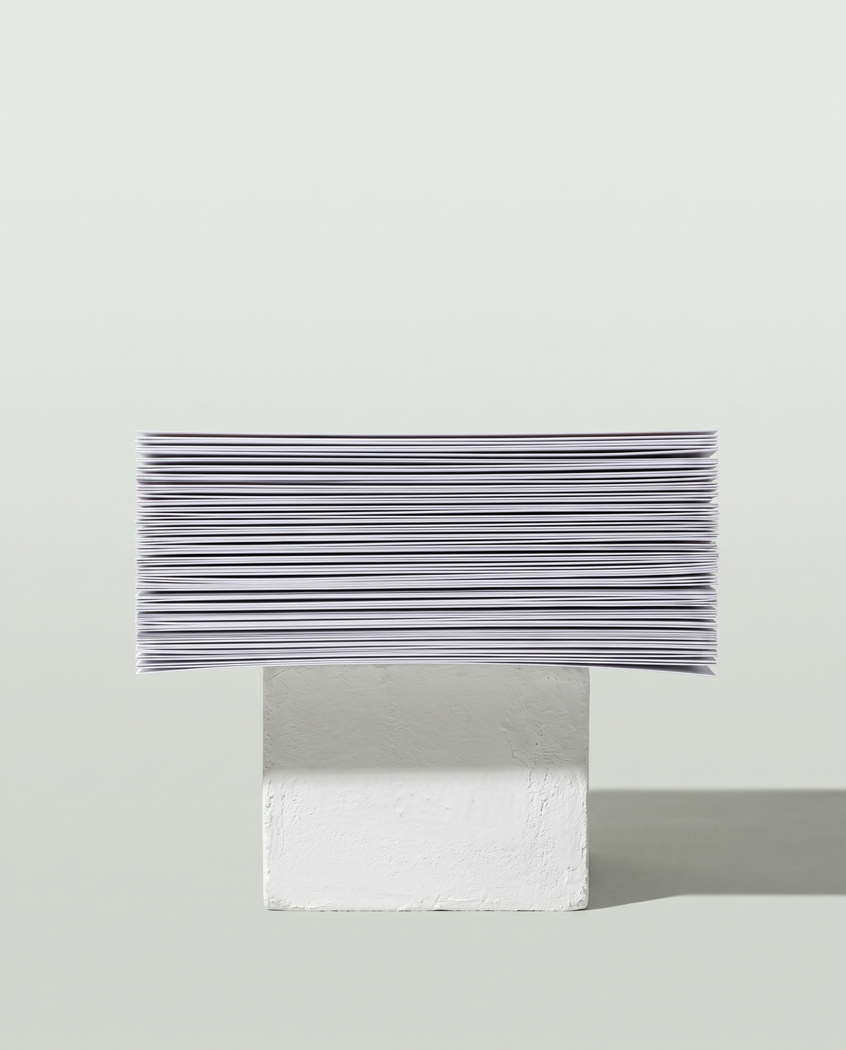 Printed pages stacked edge-on and balanced across a plaster block