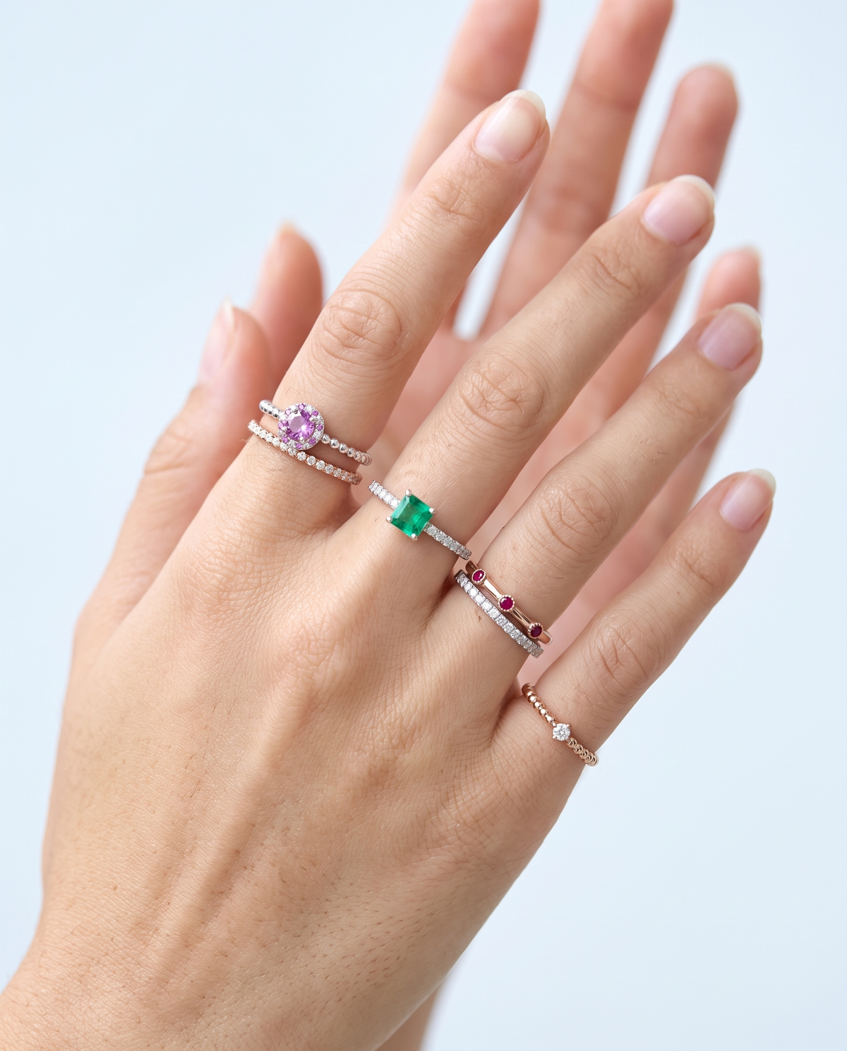 Several slender rings worn together across four fingers
