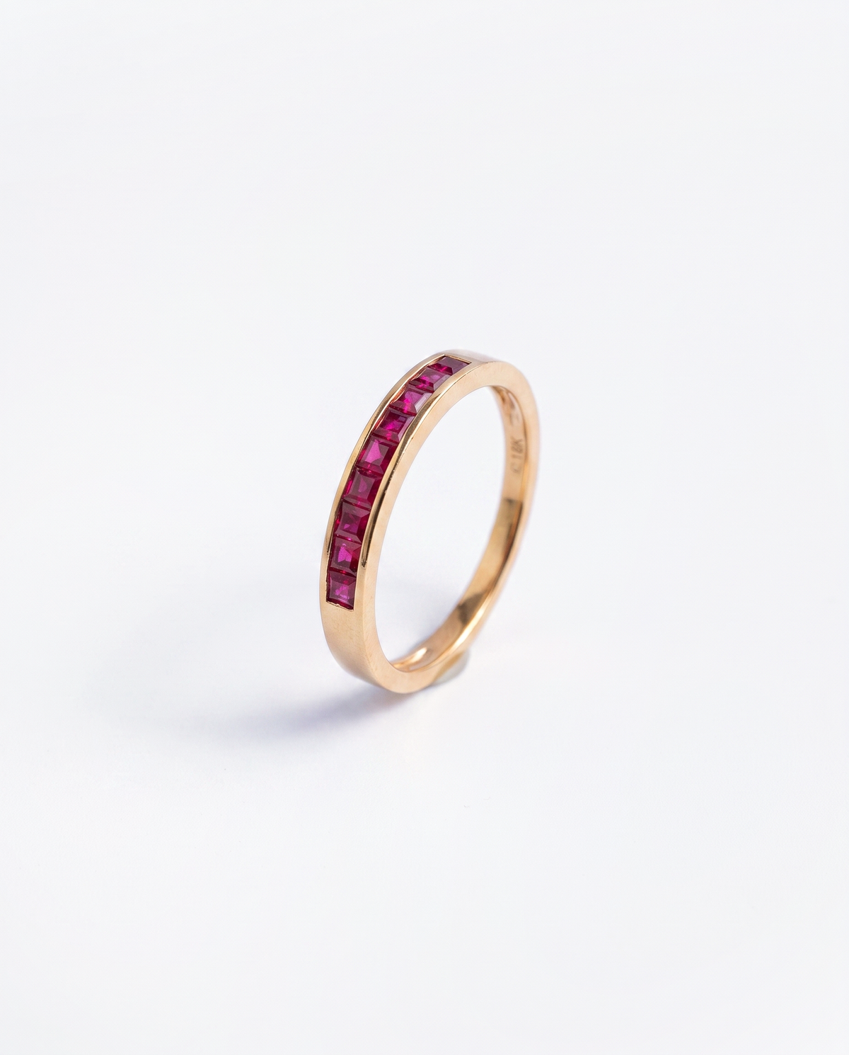 Ruby Channel, 18K yellow gold ring set with rubies, hero view of the ring upright on a plain light grey background